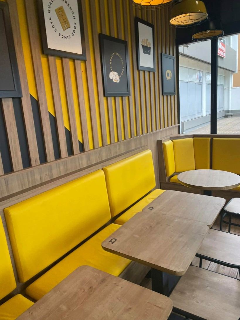 Salle d'un snack, banquettes jaunes et tables bois