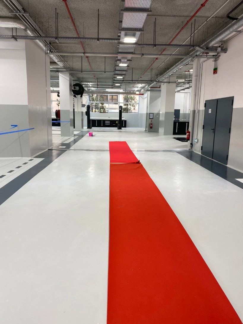 Atelier automobile en résine claire, bandes anthracite et tapis rouge déroulé