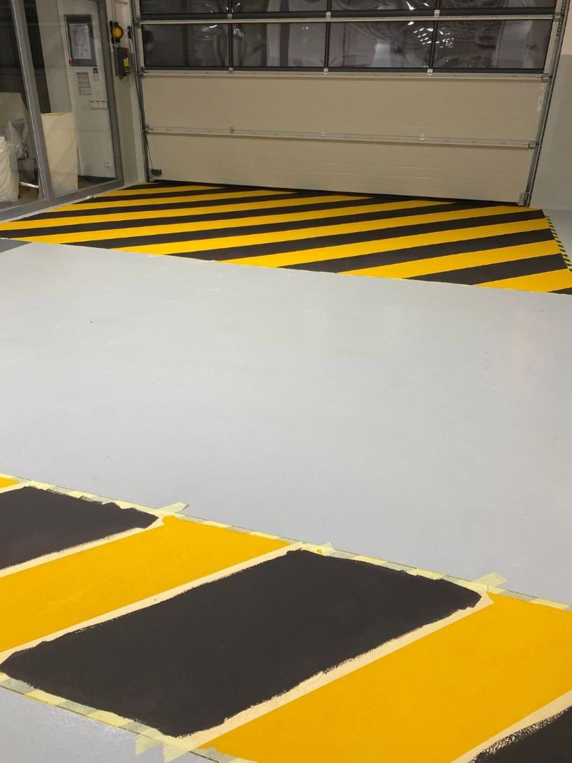Marquage jaune et noir en résine devant une porte sectionnelle
